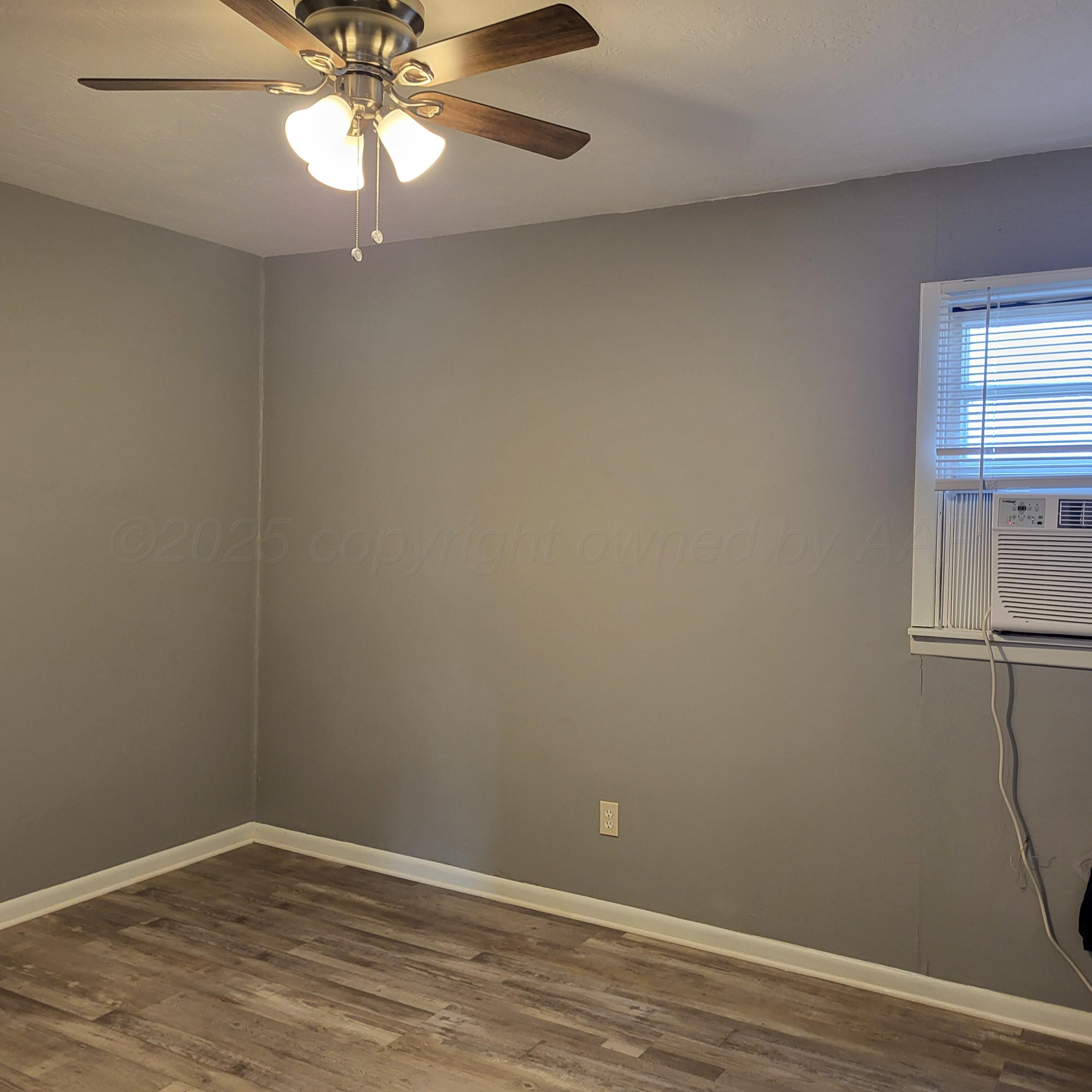 609 16th Street, Unit 4 Canyon, TX 79015 - Photo 9 of 9 an empty room with wooden floor chandelier fan and windows