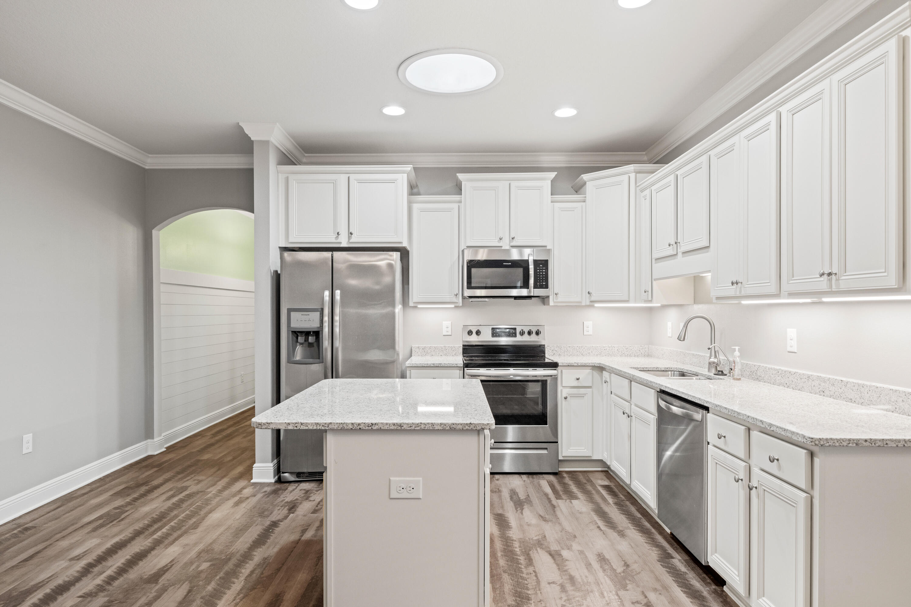 521 Cornelia Street Freeport, FL 32439 - Photo 12 of 39 a kitchen with stainless steel appliances granite countertop a sink stove refrigerator and white cabinets with wooden floor