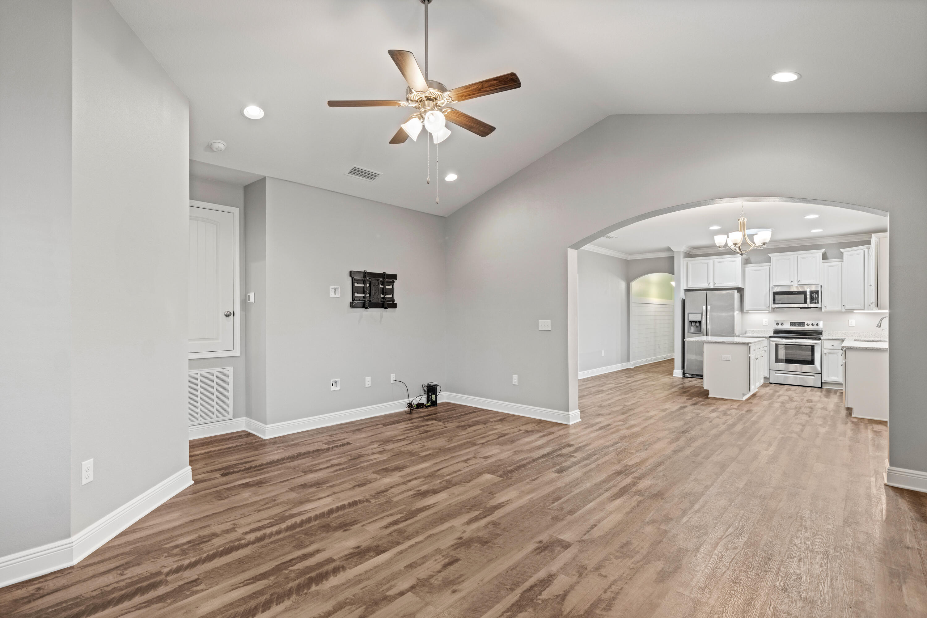 521 Cornelia Street Freeport, FL 32439 - Photo 14 of 39 an empty room with wooden floor a ceiling fan and kitchen space