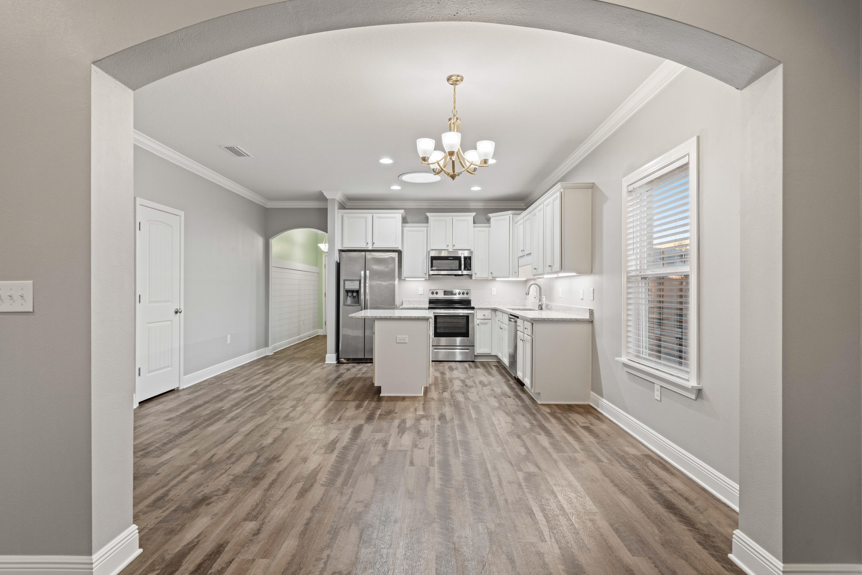 521 Cornelia Street Freeport, FL 32439 - Photo 16 of 39 a living room with stainless steel appliances furniture a chandelier and wooden floor