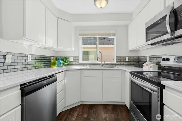 a kitchen with granite countertop white cabinets stainless steel appliances and a sink
