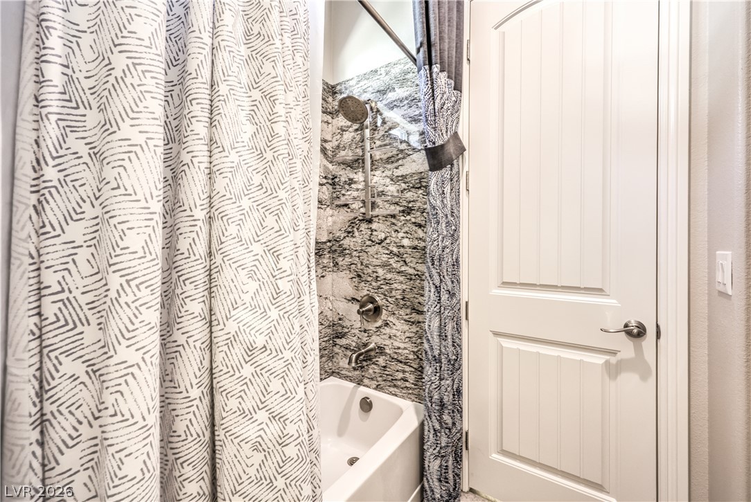 7119 Arabian Ridge Street Las Vegas, NV 89131 - Photo 37 of 73 A well-appointed bathroom features a bathtub with a shower, surrounded by stylish marble-patterned tile.