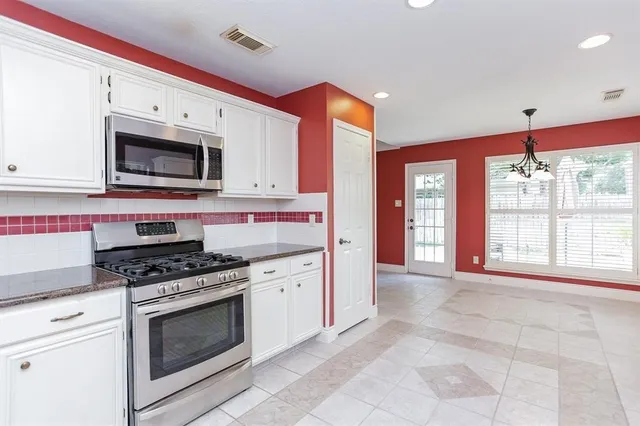 a kitchen with stainless steel appliances granite countertop a stove a microwave and a sink