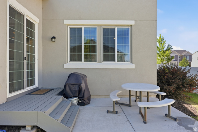 3244 West 1670th Street North Provo, UT 84601 - Photo 50 of 56 Outdoor patio featuring a grey composite deck with steps, a sliding glass door, an exterior wall light fixture, and a concrete slab