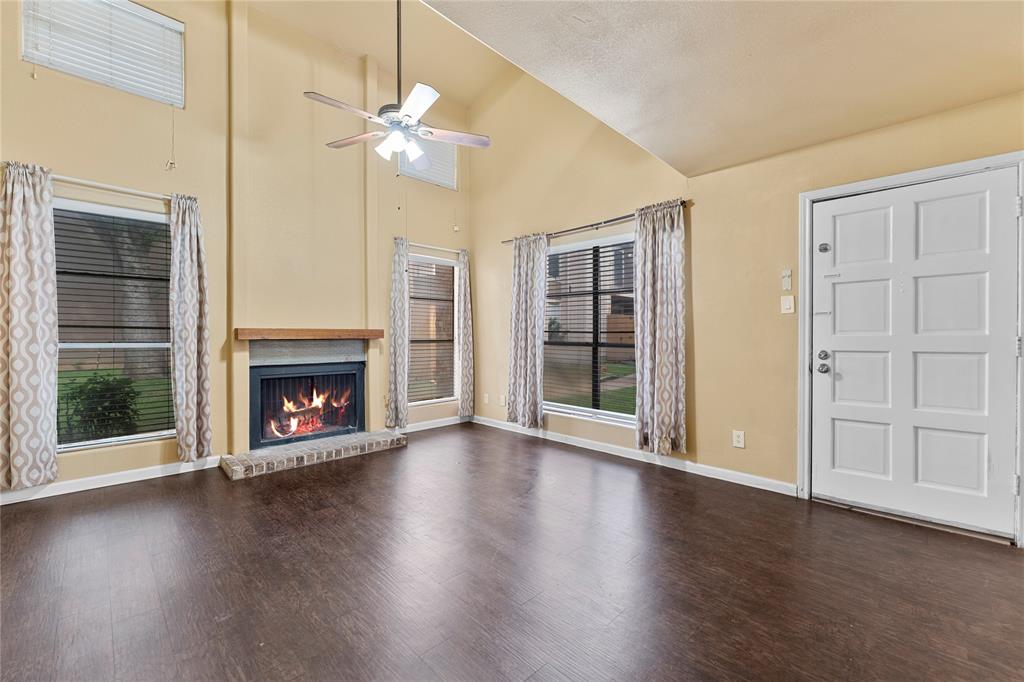 5516 Boca Raton Boulevard, Unit 310 Fort Worth, TX 76112 - Photo 1 of 19 an empty room with wooden floor a fireplace a ceiling fan and windows