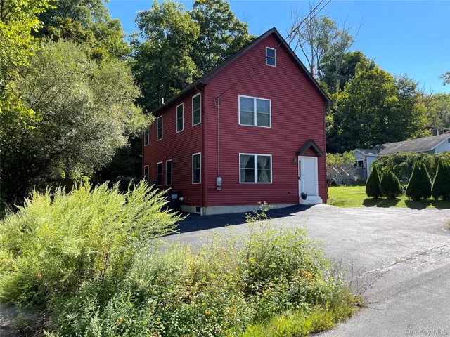 a view of a yard in front of a house with plants and large tree
