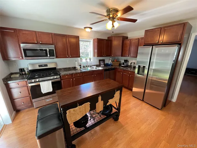 a kitchen with stainless steel appliances granite countertop a stove top oven a sink a dining table and chairs