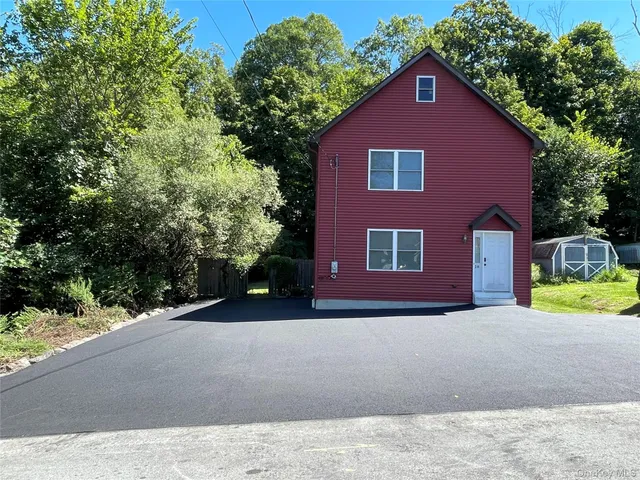 a view of brick house with a yard and large tree