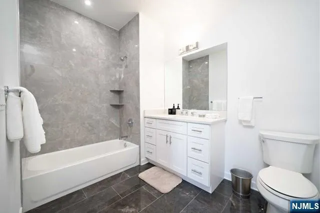 a bathroom with a toilet a sink a mirror a bathtub and vanity