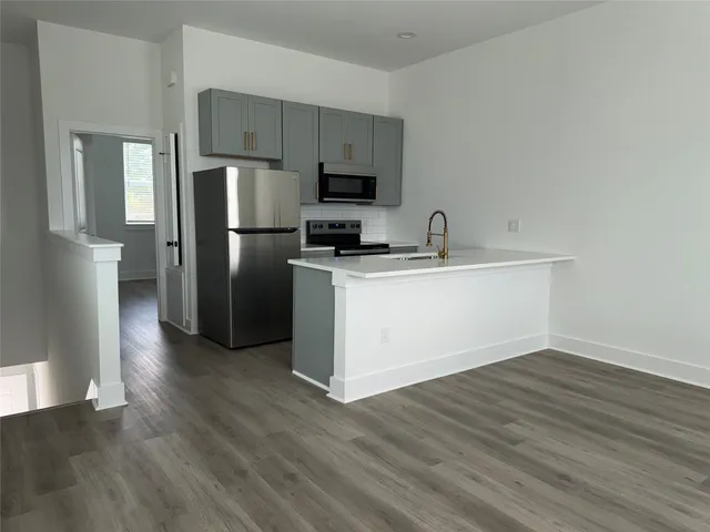 a kitchen with a refrigerator sink and wooden floor