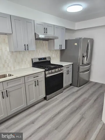 a kitchen with stainless steel appliances granite countertop a stove a sink dishwasher and white cabinets with wooden floor