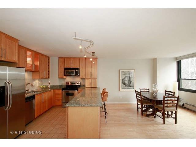 33 East Cedar Street, Unit 5F Chicago, IL 60611 - Photo 6 of 11 a kitchen with stainless steel appliances kitchen island granite countertop a table and chairs in it