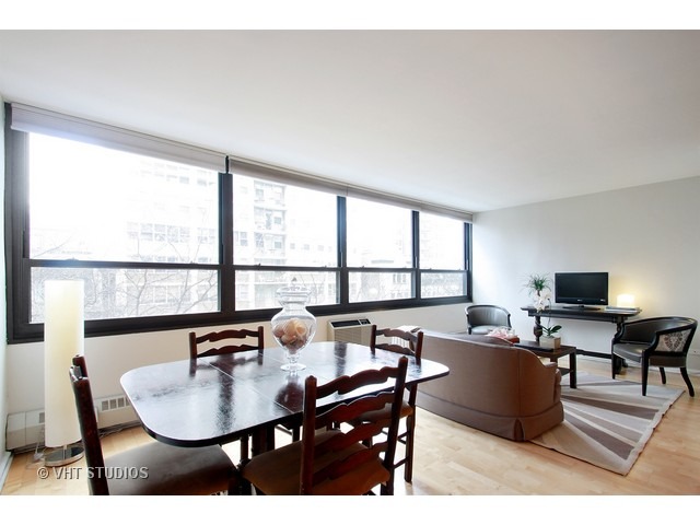 33 East Cedar Street, Unit 5F Chicago, IL 60611 - Photo 7 of 11 a living room with furniture a flat screen tv and a floor to ceiling window