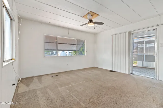 an empty room with windows and fan