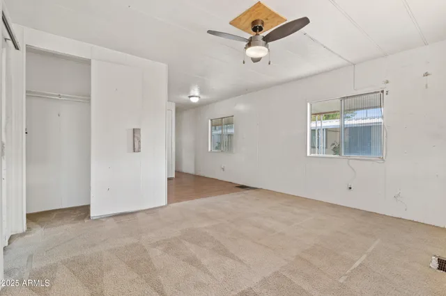 an empty room with windows and ceiling fan