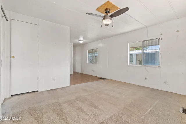 an empty room with windows and ceiling fan