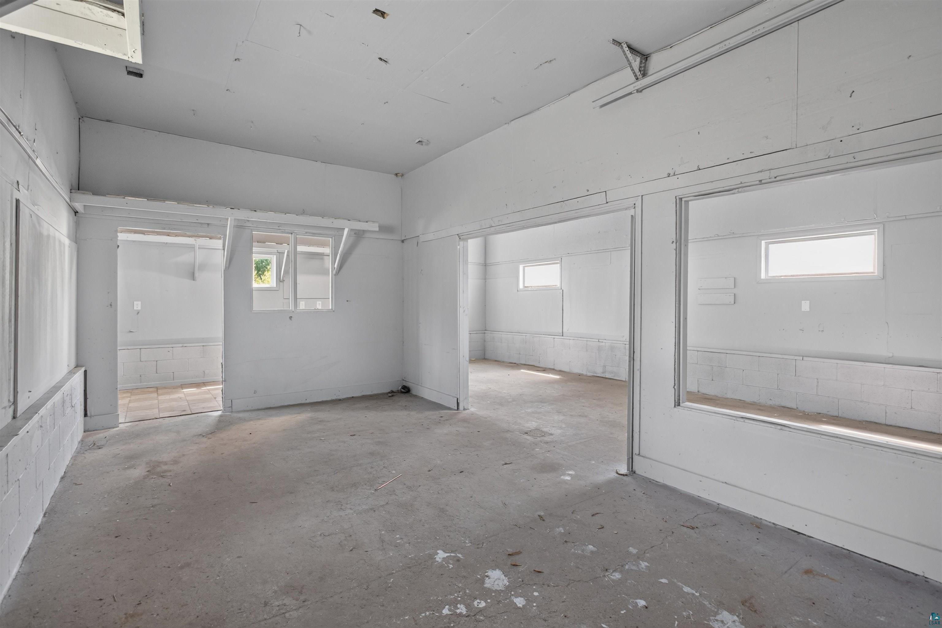 5868 Rice Lake Road Duluth, MN 55803 - Photo 30 of 39 Open interior space featuring concrete flooring, white painted block walls, and multiple window openings
