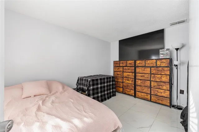 a bedroom with a bed and a flat tv screen on dresser