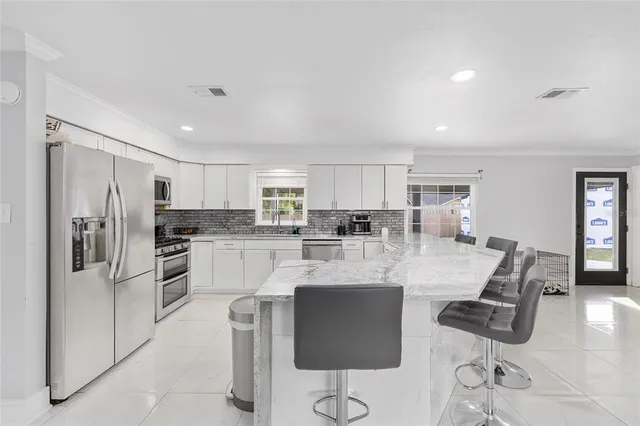 a kitchen with stainless steel appliances kitchen island granite countertop a refrigerator and cabinets