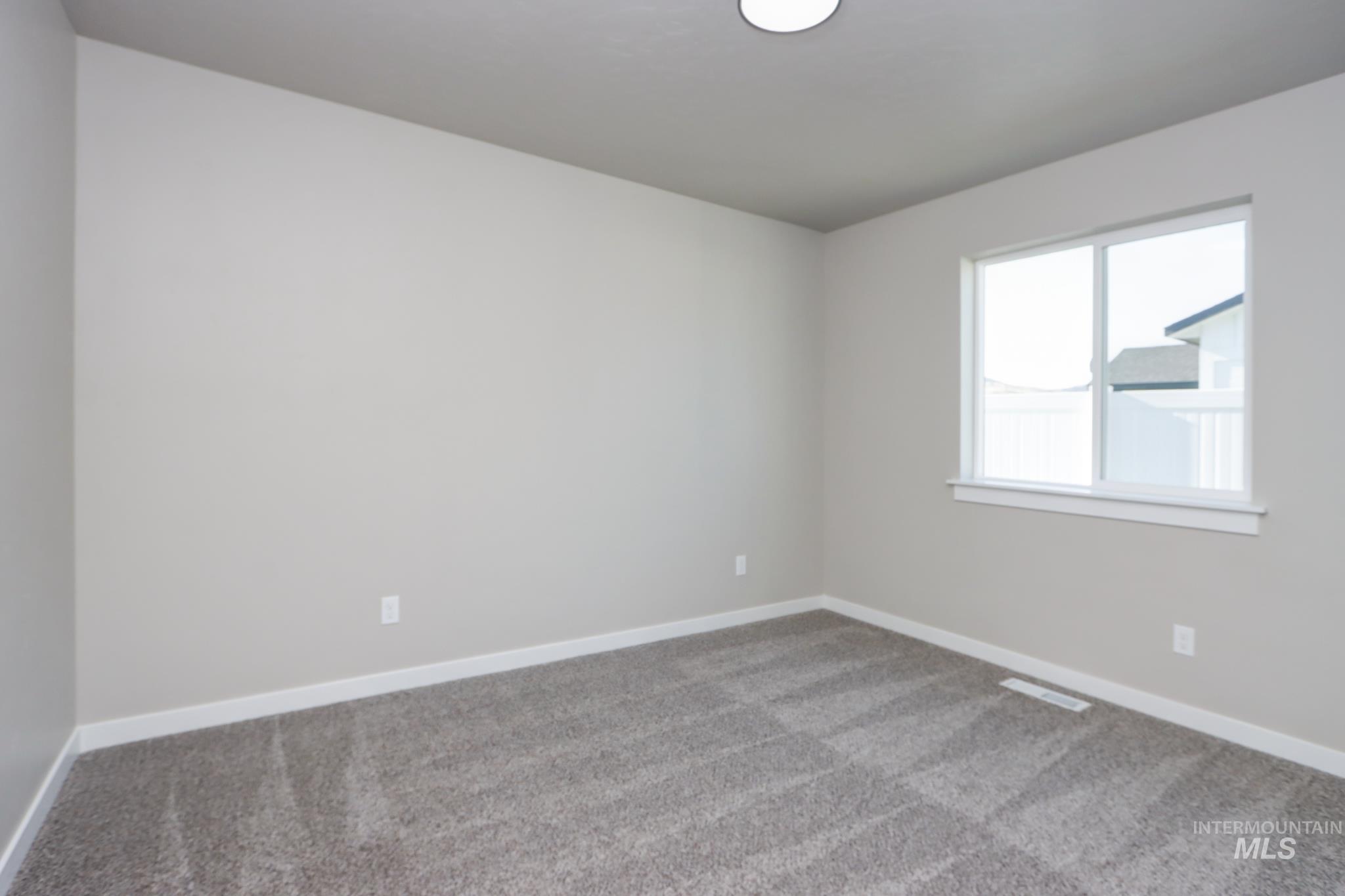 848 North 5th Street Nyssa, OR 97913 - Photo 31 of 49 Neutral-toned room featuring a large window with white trim, light gray wall paint, and gray carpet flooring