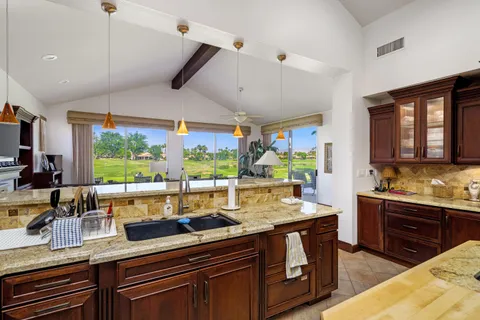 a kitchen with stainless steel appliances kitchen island granite countertop a sink and wooden cabinets