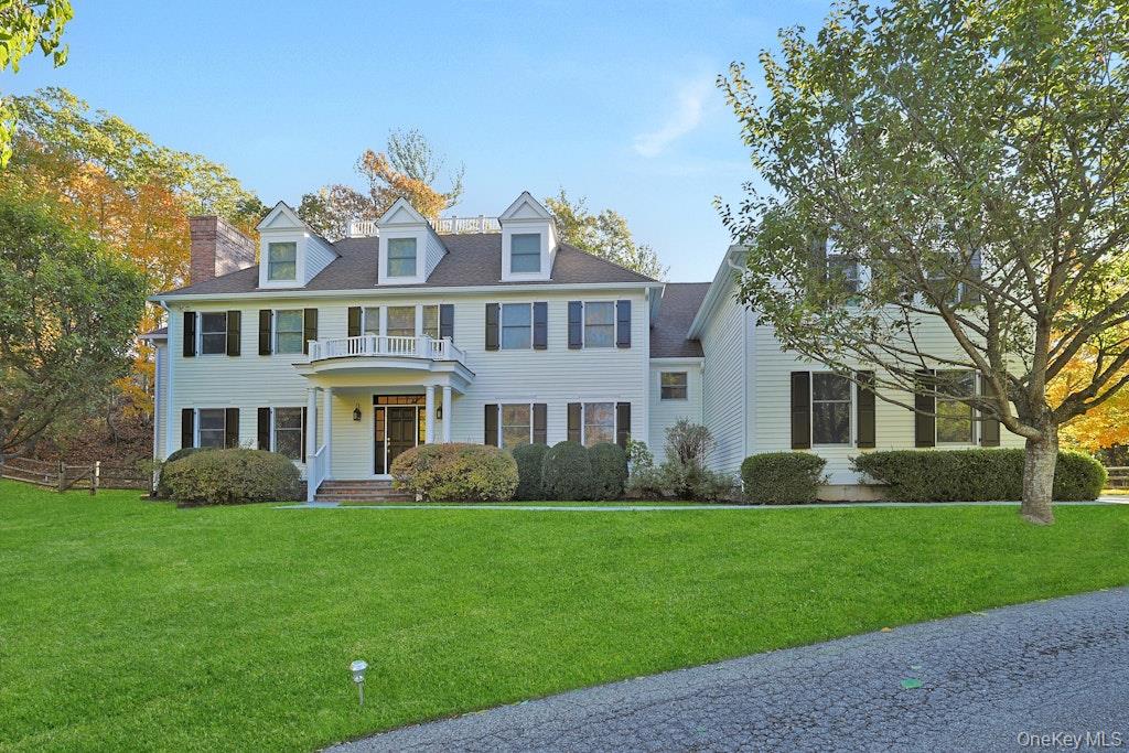 View of front of home with a front yard, a chimney, and a balcony