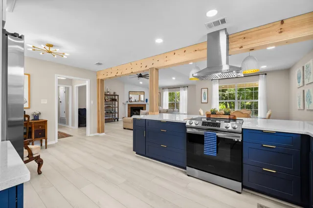 a kitchen with stainless steel appliances kitchen island granite countertop a table chairs in it and wooden floors