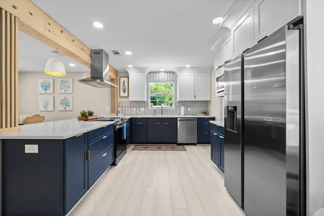 a kitchen with stainless steel appliances kitchen island granite countertop a table chairs in it and wooden floors