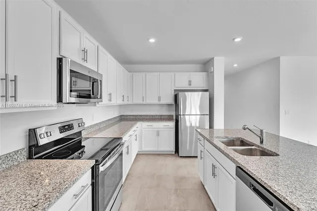 a kitchen with stainless steel appliances granite countertop a sink stove microwave and refrigerator