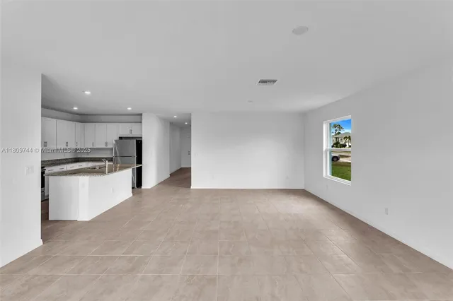 a view of kitchen with refrigerator cabinets and window