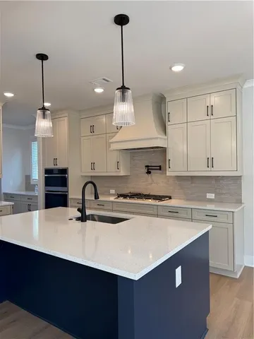 a kitchen with kitchen island a sink a stove a counter space and cabinets
