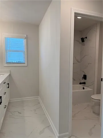 a bathroom with a granite countertop sink a toilet and shower