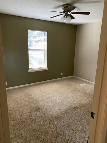a view of a kitchen with white cabinets and a window