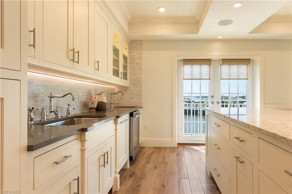 451 Bayfront Place, Unit 5407 Naples, FL 34102 - Photo 11 of 38 Kitchen with crown molding, light wood-style flooring, recessed lighting, dark stone counters, and glass fronted cabinets