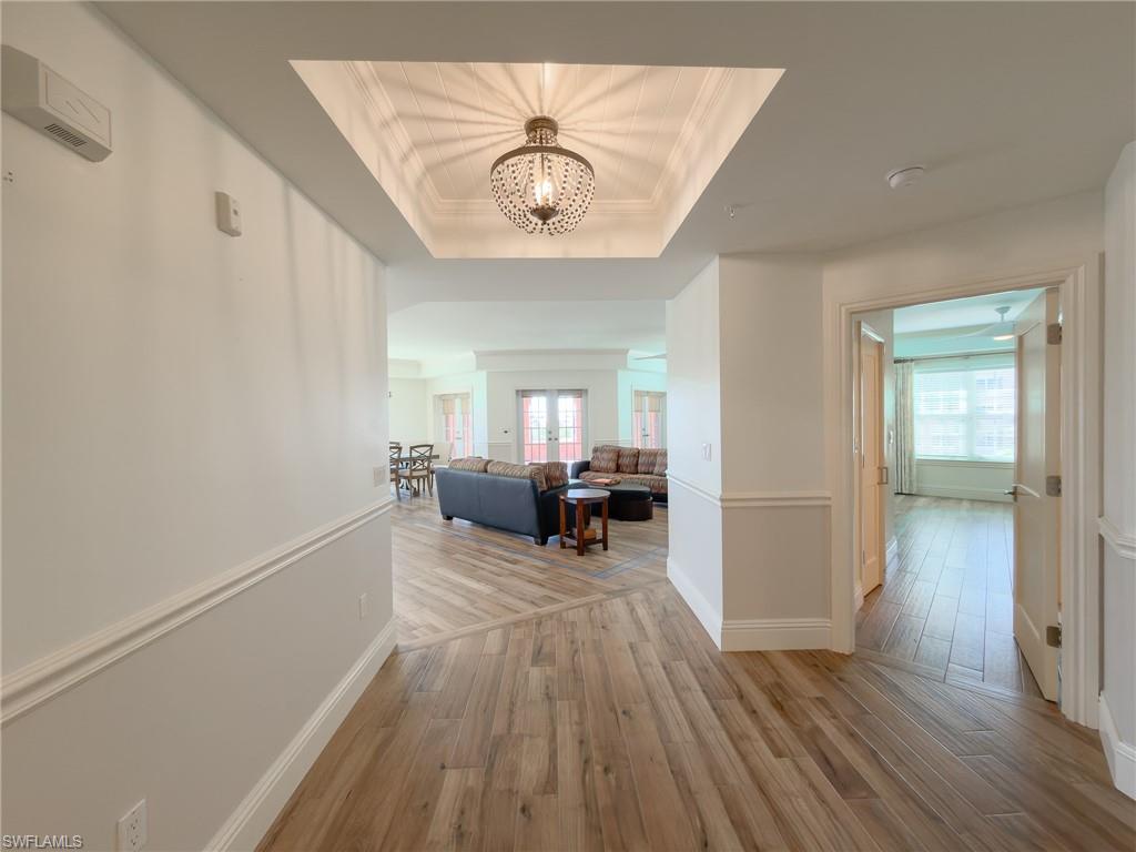 451 Bayfront Place, Unit 5407 Naples, FL 34102 - Photo 35 of 45 Corridor with crown molding, light wood-type flooring, a raised ceiling, and hanging lights