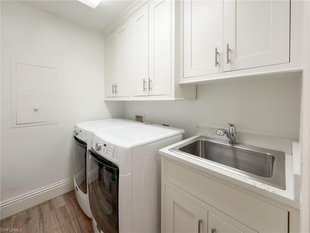 451 Bayfront Place, Unit 5407 Naples, FL 34102 - Photo 36 of 45 Laundry room featuring washing machine and clothes dryer, light wood-style floors, and cabinet space