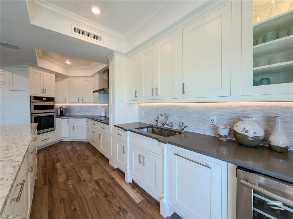 451 Bayfront Place, Unit 5407 Naples, FL 34102 - Photo 4 of 45 Kitchen featuring white cabinetry, backsplash, dark wood-type flooring, stainless steel double oven, and dark stone counters
