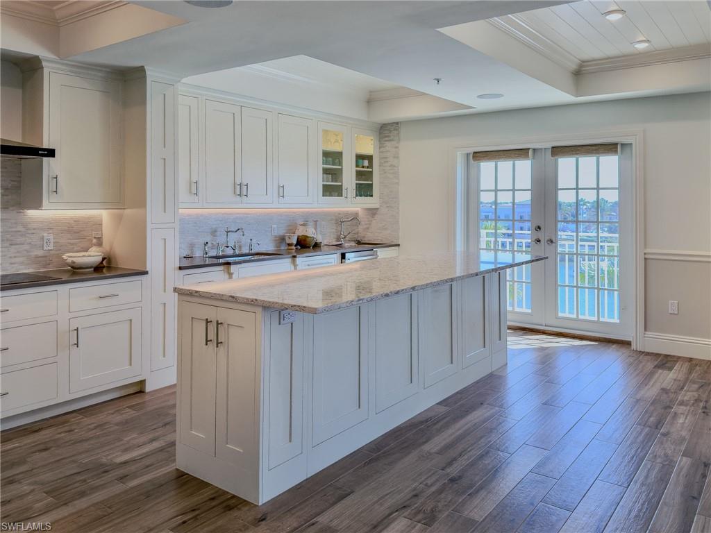 451 Bayfront Place, Unit 5407 Naples, FL 34102 - Photo 5 of 45 Kitchen featuring crown molding, white cabinets, glass insert cabinets, dark wood finished floors, and a tray ceiling