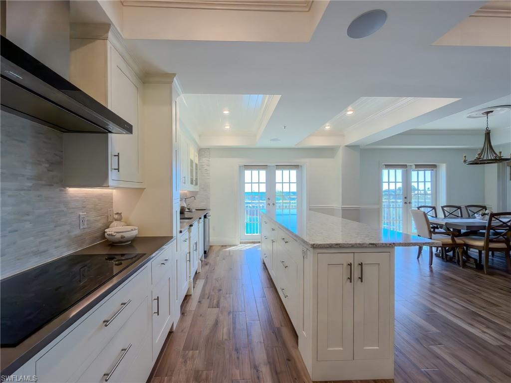 451 Bayfront Place, Unit 5407 Naples, FL 34102 - Photo 7 of 45 Kitchen with white cabinetry, black electric stovetop, dark wood-type flooring, a center island, and a tray ceiling