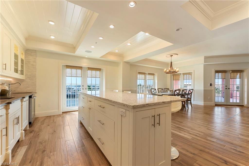 451 Bayfront Place, Unit 5407 Naples, FL 34102 - Photo 10 of 38 Kitchen with french doors, light wood-style floors, white cabinets, light stone counters, and a raised ceiling