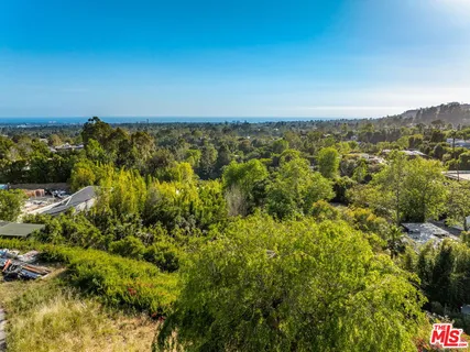 an aerial view of residential houses with outdoor space and trees