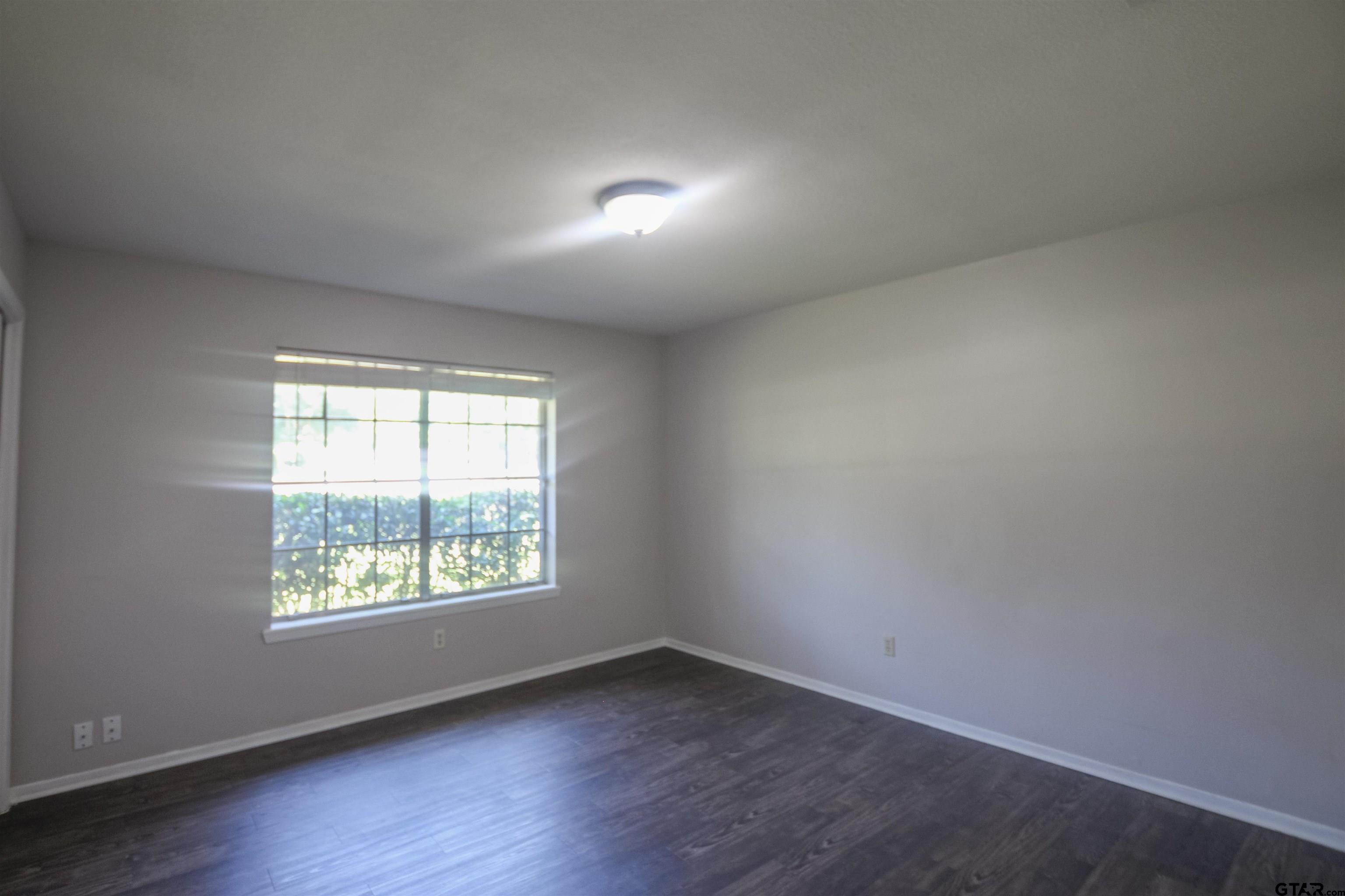 8524 Radcliffe Drive Tyler, TX 75703 - Photo 18 of 26 an empty room with wooden floor and windows