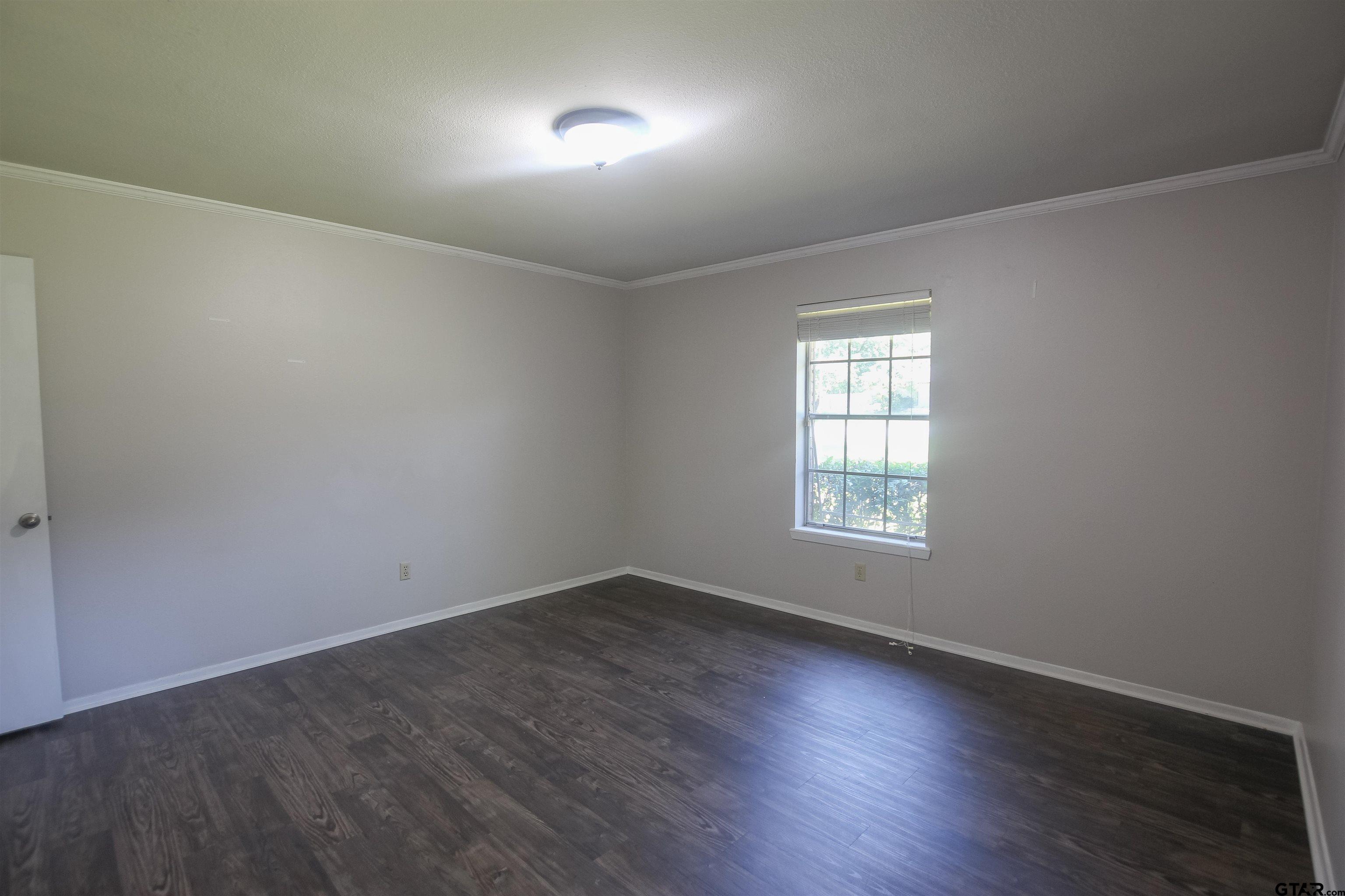8524 Radcliffe Drive Tyler, TX 75703 - Photo 23 of 26 an empty room with wooden floor and windows