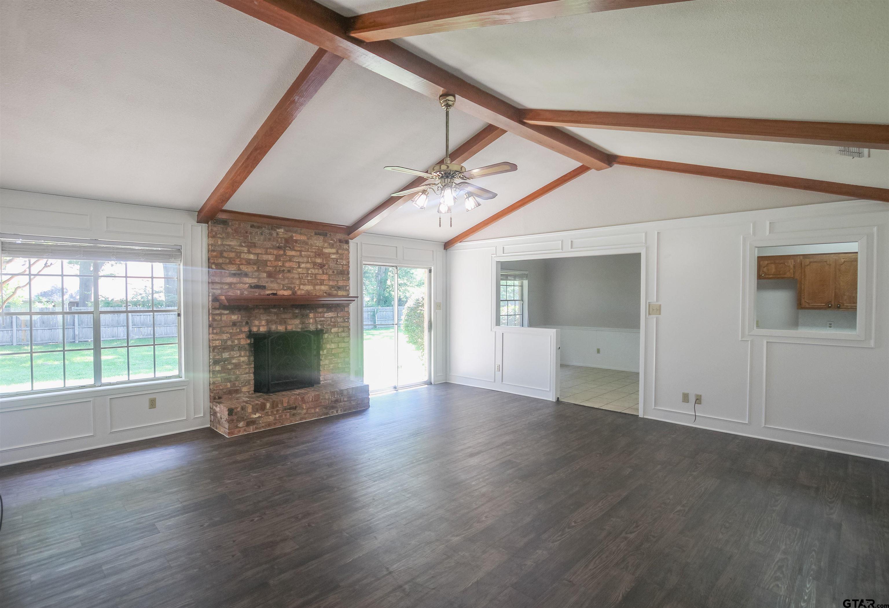 8524 Radcliffe Drive Tyler, TX 75703 - Photo 3 of 26 an empty room with wooden floor a fireplace and windows