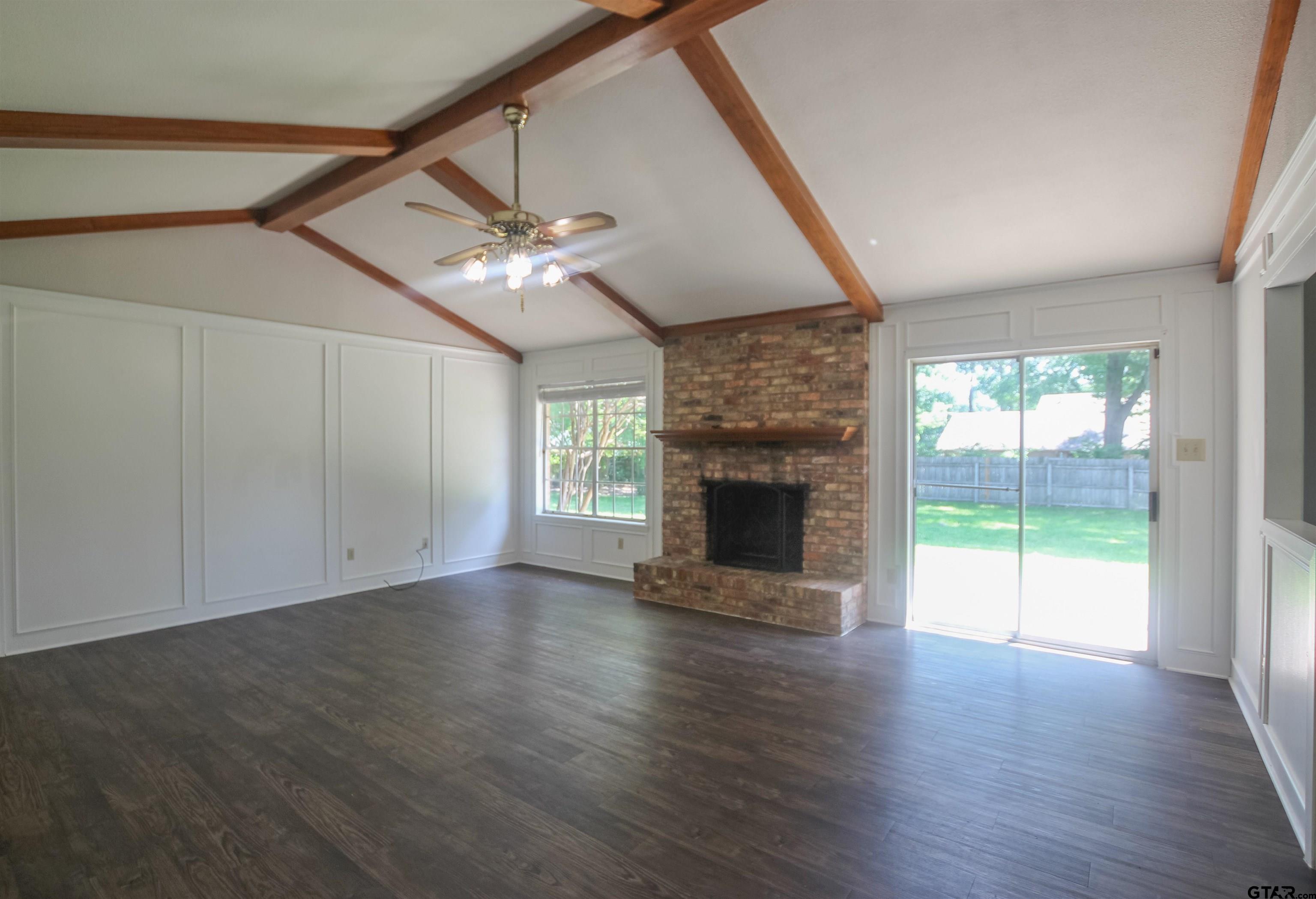 8524 Radcliffe Drive Tyler, TX 75703 - Photo 4 of 26 an empty room with windows a fireplace and wooden floor