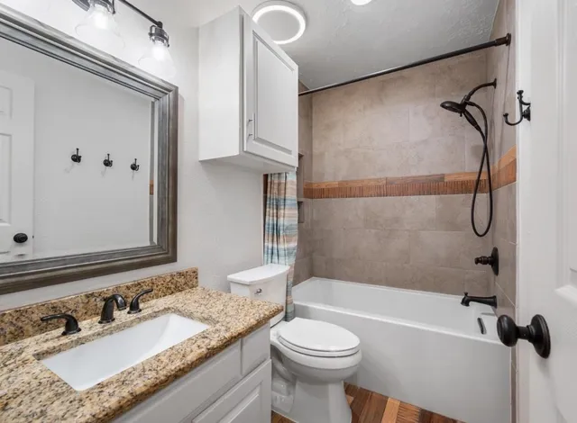 a bathroom with a granite countertop sink toilet and shower