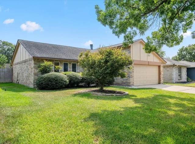 a view of a house with a yard and a large tree