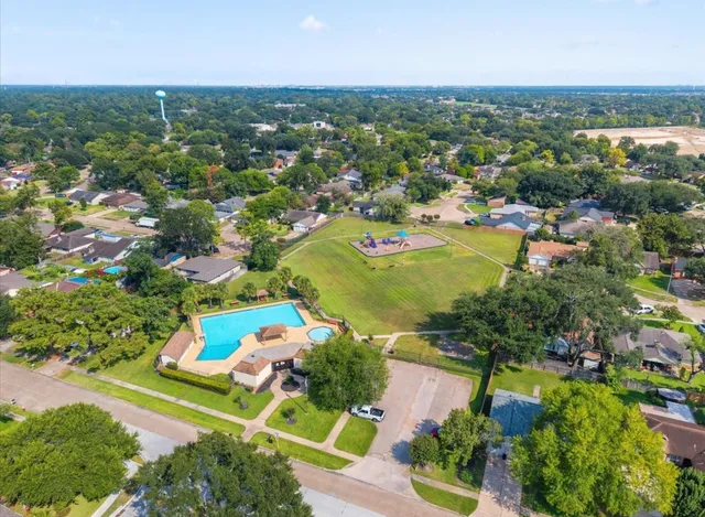 an aerial view of residential houses with outdoor space and trees
