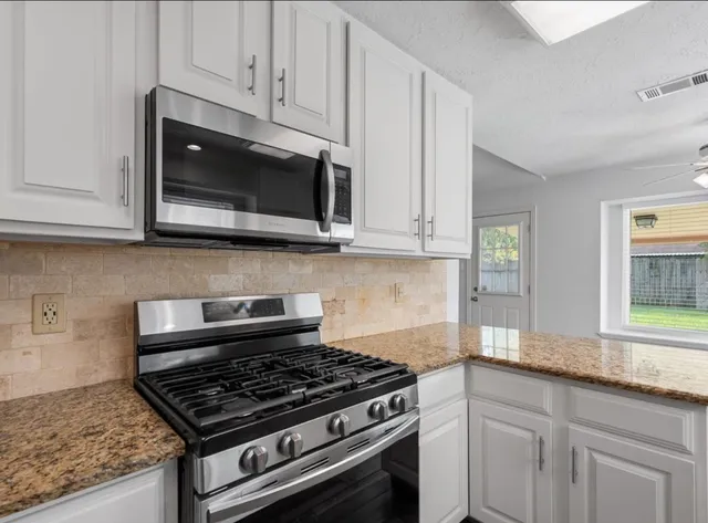 a kitchen with granite countertop a stove and a microwave