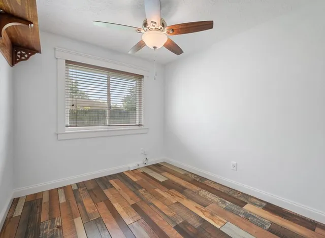 an empty room with a window and ceiling fan